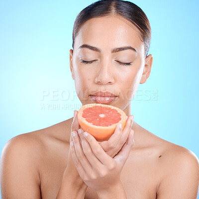 Buy stock photo Face, skincare and woman with grapefruit and eyes closed in studio isolated on a blue background. Wellness, food or female model holding healthy fruit for natural vitamin c, nutrition or healthy skin