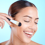 Woman, beauty and makeup brush in studio, smile and cosmetics for skincare, face and happiness. Happy black woman, model and cosmetic foundation for powder, glow and wellness by blue background