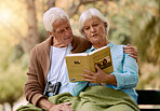 Park, senior and couple reading a book, relaxing and bonding outdoors with blanket. Love, retirement and elderly man and woman studying literature, story or novel and enjoying quality time together.