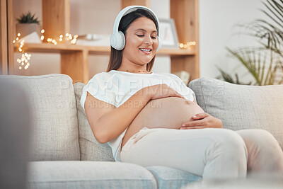 Buy stock photo Pregnant, music and relax with a woman sitting on a sofa in their living room of her home expecting a baby. Pregnancy, wellness and stomach with a young female streaming audio alone in her apartment