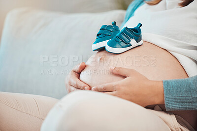 Buy stock photo Pregnant, belly and baby shoes on sofa for woman, future mother or ready for kids, children or motherhood. Woman, pregnancy or kid sneakers for dream, vision or preparation at family home for child