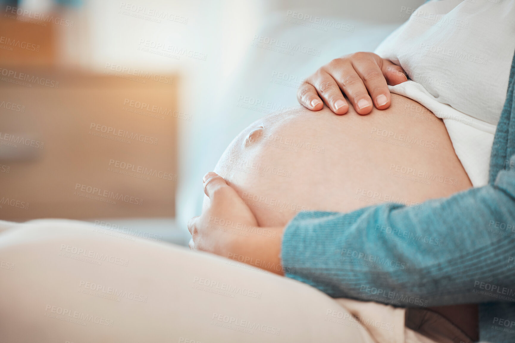 Buy stock photo Hands, stomach and pregnant with a woman sitting in the bedroom of her home alone while touching her belly. Mother, love and baby with a female parent holding her tummy while on the bed to relax