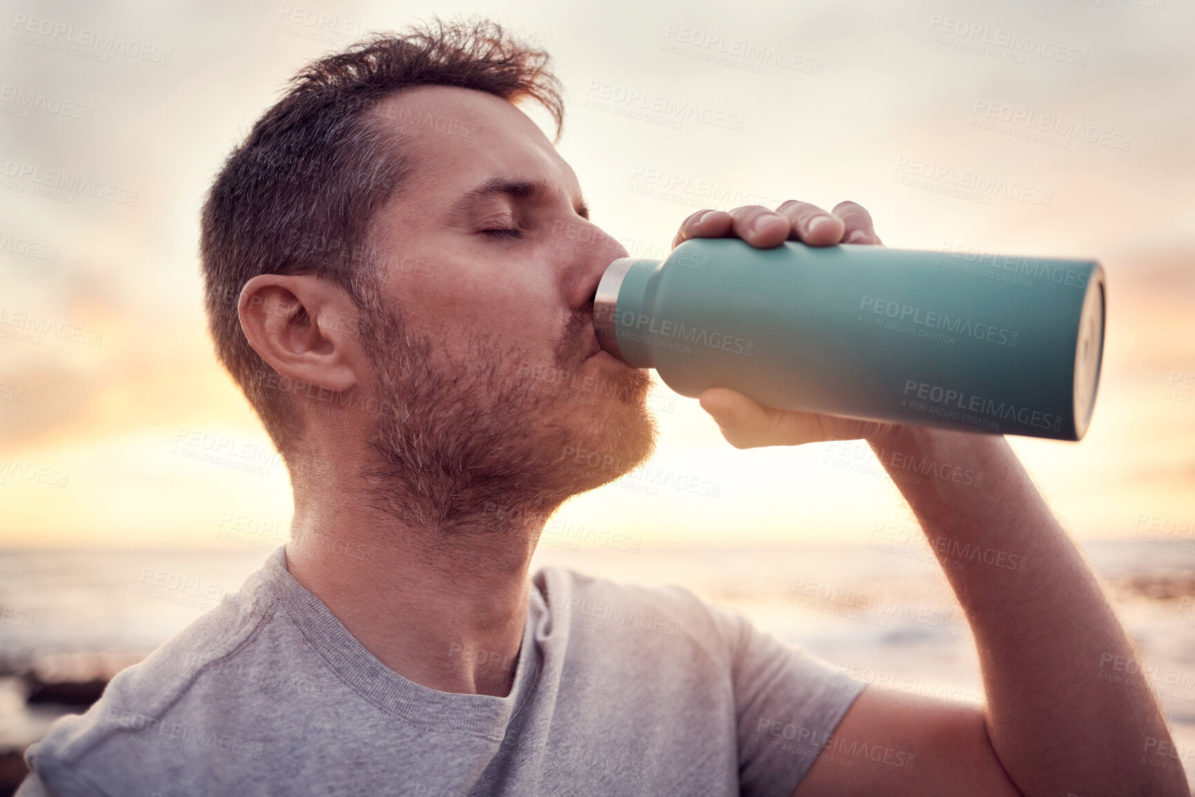 Buy stock photo Man, fitness and water bottle with sunset beach background for thirst, hydration and healthy lifestyle while outdoor for exercise, workout and training. Male athlete drinking refreshment in nature