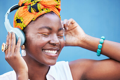 Buy stock photo Music, freedom and headphones with a black woman outdoor on a blue wall background enjoying a track. Radio, relax and happy with a young female streaming or listening to audio on a wireless headset