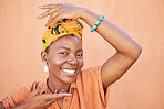 Face portrait, fashion and black woman with turban in studio on an orange background. Beauty pose, hands frame and makeup of happy female model from Nigeria in stylish traditional African head scarf.