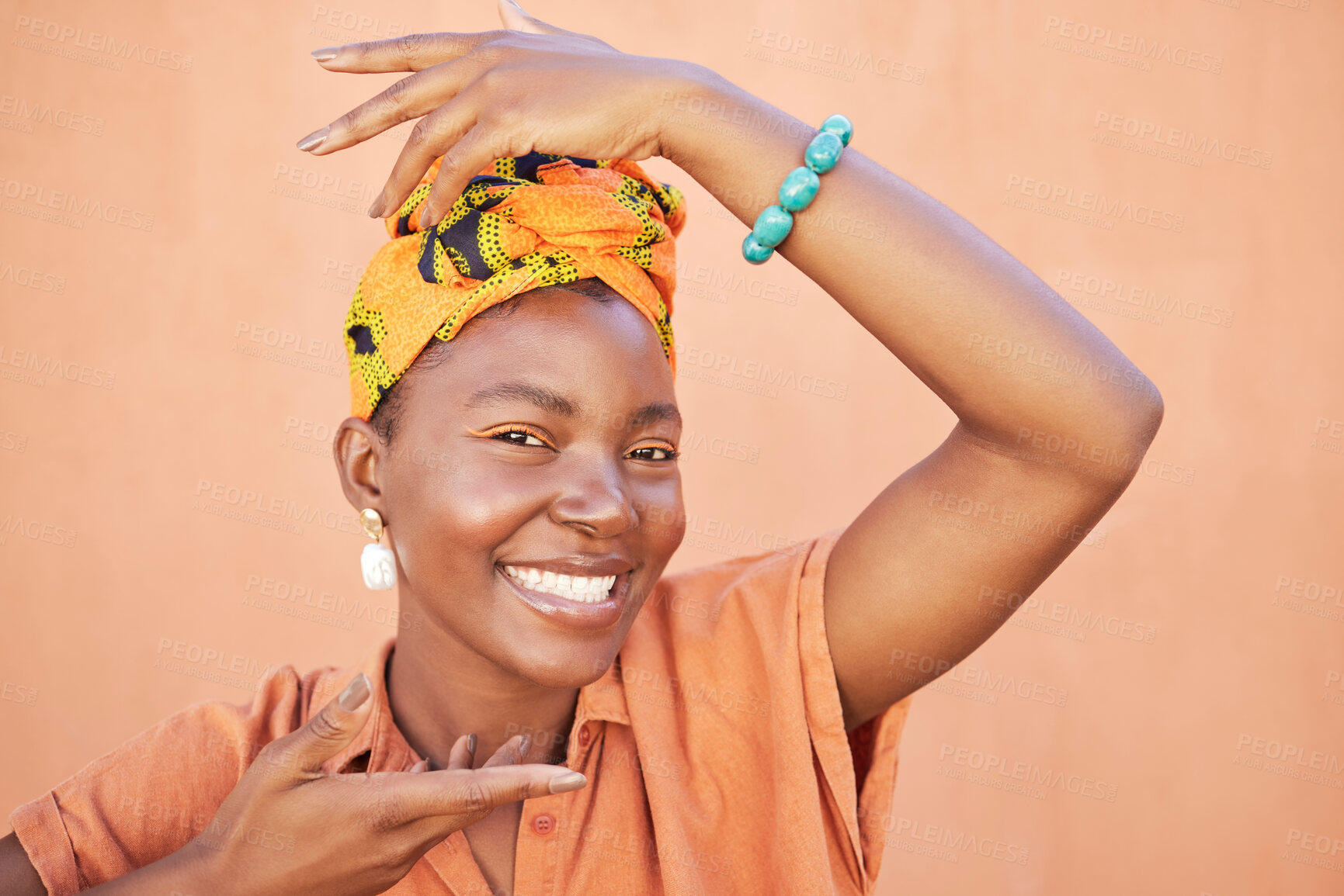 Buy stock photo Face portrait, fashion and black woman with turban in studio on an orange background. Beauty pose, hands frame and makeup of happy female model from Nigeria in stylish traditional African head scarf.