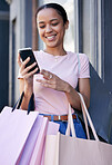 Shopping, smartphone and black woman with shopping bag at outdoor mall, retail and fashion boutique with technology and communication. Mobile phone, shop and customer, happy and check social media.