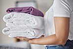 Hands, woman and pile of towel, laundry and holding a stack of neat, folded laundry in home. Female cleaning clothing, olding and pile of fresh, cleaned towels in house, cleaning service and cleaner