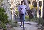 Fitness, nature and black woman running for exercise with endurance, focus and health in a forest. Sports, athlete and African lady doing cardio workout or training for race, marathon or competition.