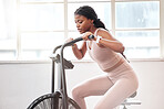 Black woman, cycling and exercise bike in gym, cardio workout and fitness challenge, training and healthy performance. Female on stationary air bicycle machine with speed, energy and strong power 