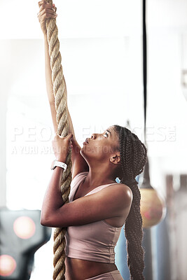 Buy stock photo Black woman, fitness and rope climbing at gym for cross workout training for strength, energy and focus of a strong athlete. Female doing climb exercise for strength, muscle and energy with endurance