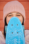 Skateboard, young face and woman hiding with winter beanie, clothes and gen z fashion, hipster culture and happiness in city. Portrait, happy and shy skater girl, eyes and relax for fun at skate park