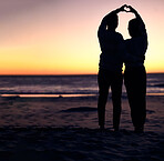 Couple, sunset silhouette and beach with heart sign hands, bonding and love on vacation for honeymoon. Man, woman and romantic hand signal by ocean with dusk sunshine for romance, together and nature