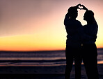 Couple, silhouette and sunset beach with heart shape hands for love, commitment and care on a romantic date, holiday or honeymoon at sea. Man and woman together on ocean vacation for nature travel