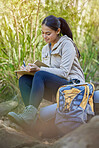 Hiking, travel and woman writing in book sitting outdoors in nature. Freedom, hiker and happy female from India with personal diary, notebook or journal to write ideas, thoughts or journey experience