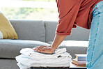 Laundry, chores and hands of a woman with clothes, clean towels and clothing from the wash in the living room. Working, spring cleaning and cleaner with washing pile, housework and housekeeping