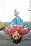 Woman, sofa and upside down with headphones, smile or music in portrait to relax in lounge. Happy lady, couch or audio for happiness, streaming podcast or internet radio in home living room in Mexico