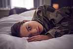 Woman, stress and depression lying on bed in military suffering from insomnia or mental disorder at home. Depressed female soldier in mental health issues, sleepless or nightmare in the bedroom