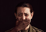 Abuse, fear and hand over the mouth of a woman in studio on a dark background to stop gender violence. Portrait, mouth and silence with a female victim or hostage as a symbol of domestic violence