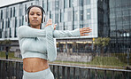 Fitness, stretching and woman with headphones in city rain for music inspiration, health and wellness in focus, energy and goal portrait. Sports, athlete or black woman listening to audio in street 