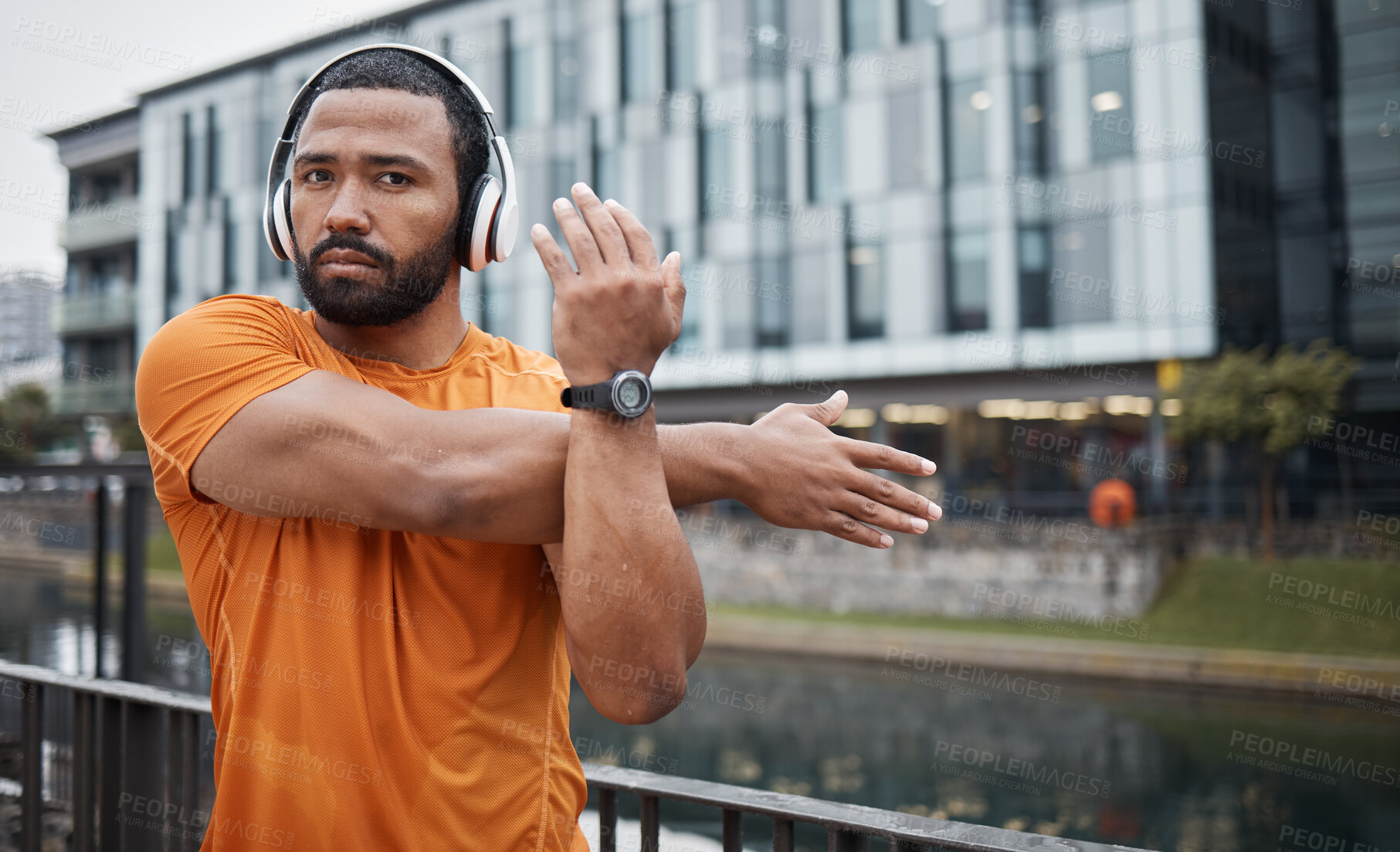Buy stock photo Fitness, black man stretching and headphones, runner in city with music for motivation and exercise with focus, strong and cardio. Workout, training and run in urban cityscape, start and warm up.