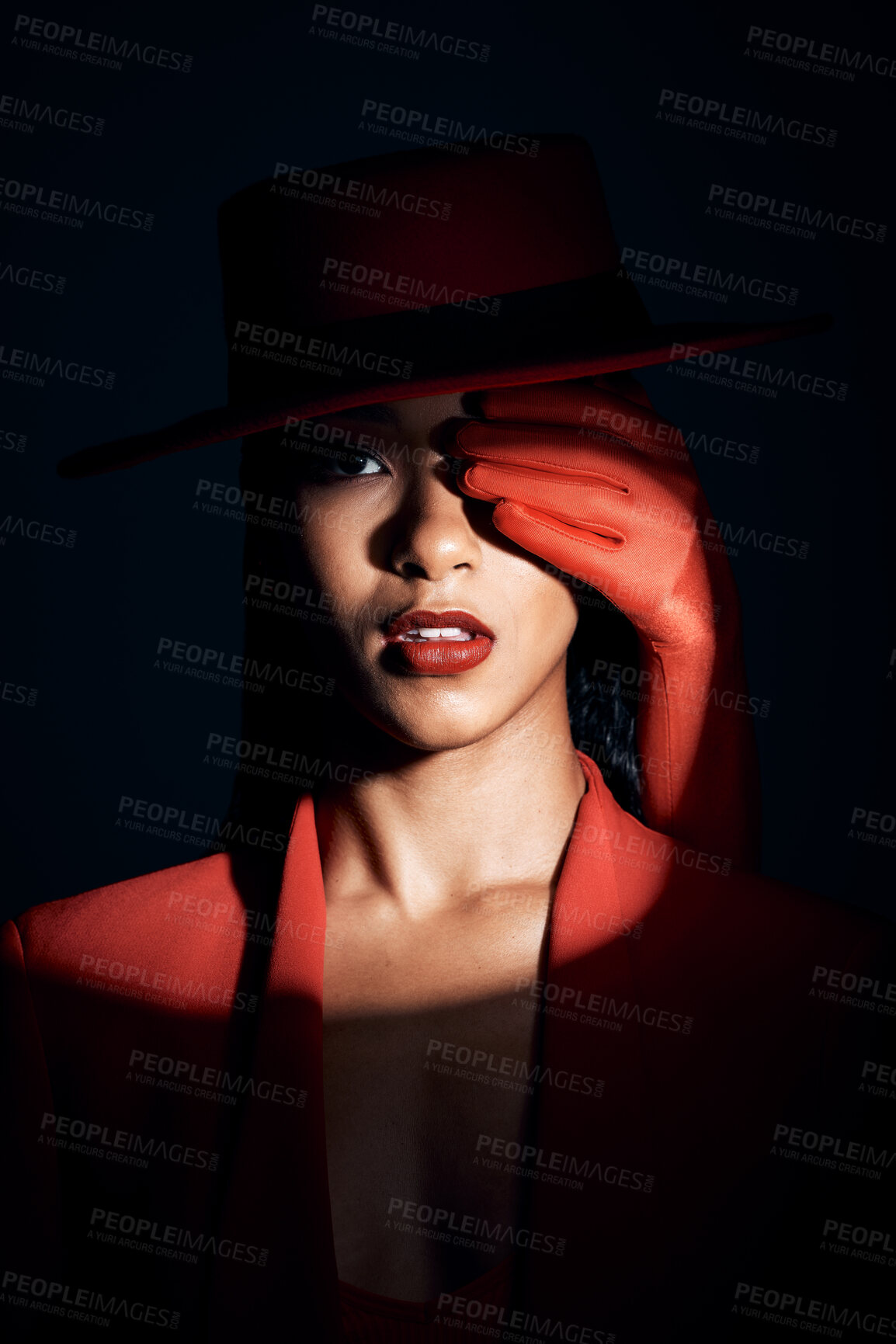 Buy stock photo Fashion, beauty and spotlight on face of woman for creative, makeup and art with shadow. Designer, luxury and retro with mystery girl model in red suit for magic, privacy and dramatic in studio