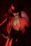 Woman, fashion hat and spotlight for suit, sexy and mystery in studio for beauty, punk aesthetic and cosmetics. Fashion model girl, cyberpunk design or unique with dark cosmetic by red background