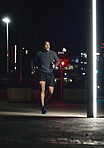 Running, fitness and man in night city for training muscle, body goals and lose weight challenge in motivation, energy and speed. Sports, athlete and cardio runner in dark urban street and spotlight