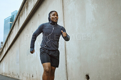 Buy stock photo Black man, fitness and running in the city with earphones listening to music during cardio workout. Active African American man runner enjoying audio track, healthy exercise or training in urban town