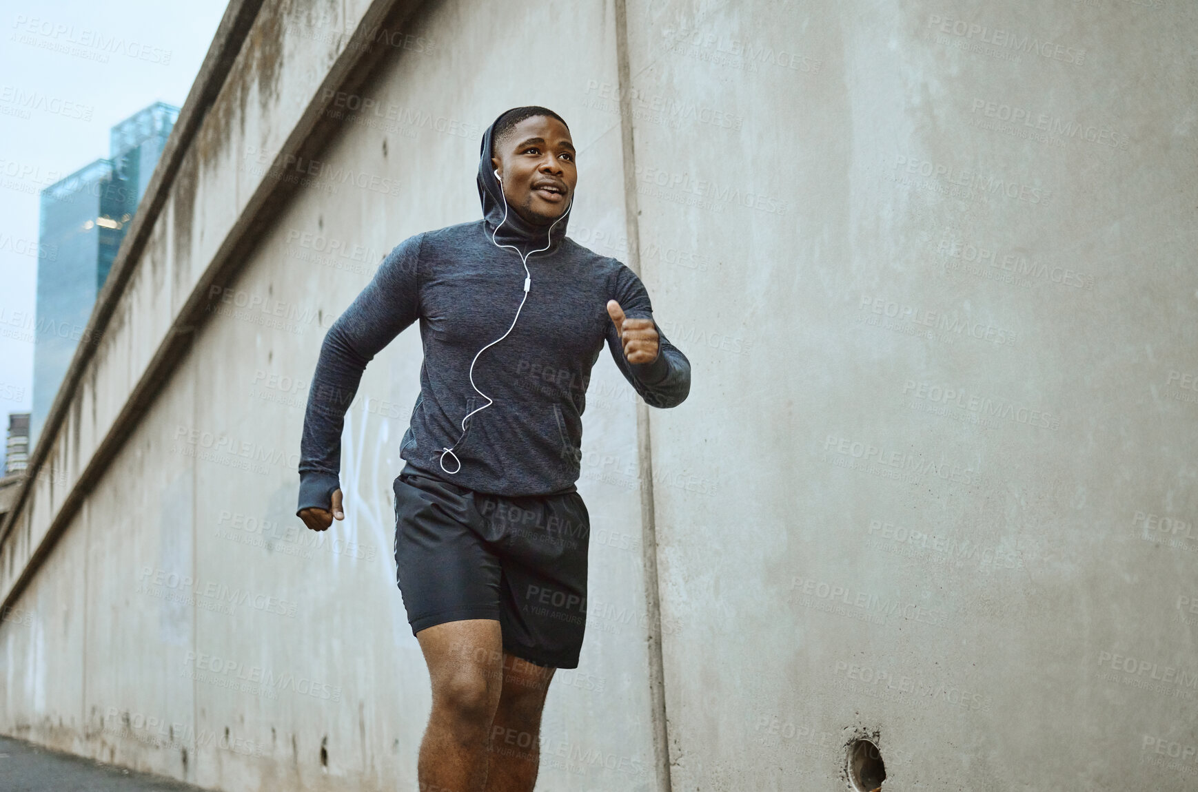 Buy stock photo Black man, fitness and running in the city with earphones listening to music during cardio workout. Active African American man runner enjoying audio track, healthy exercise or training in urban town