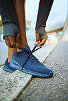 Workout, fitness and man tying shoes on feet on city street before marathon training or running. Health, wellness and sports footwear, motivation for exercise for black man athlete or urban runner.
