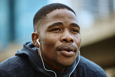 Buy stock photo Face, music earphones and black man in city streaming radio or podcast on break after exercise. Sports, fitness and male from Nigeria listening to workout song while thinking of running in winter.