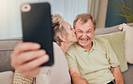 Senior, kiss and phone selfie of a couple with love, care and happiness on a living room sofa. Happy, smile and marriage of a wife and man together on wifi with mobile phone photo for social media
