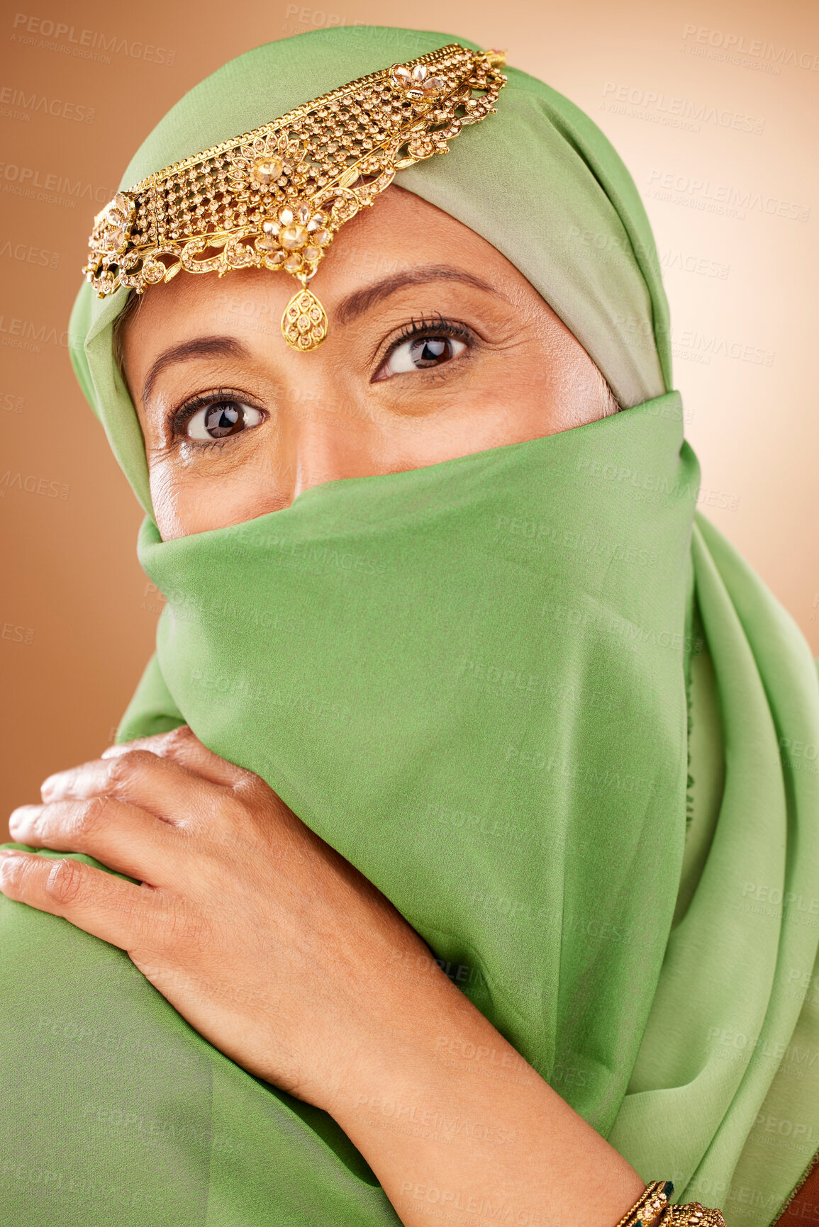 Buy stock photo Fashion, tradition and face of a muslim woman in studio with traditional jewelry and burka. Beauty, islam and portrait of mature lady with islamic hijab scarf or arabic jewellery by brown background.