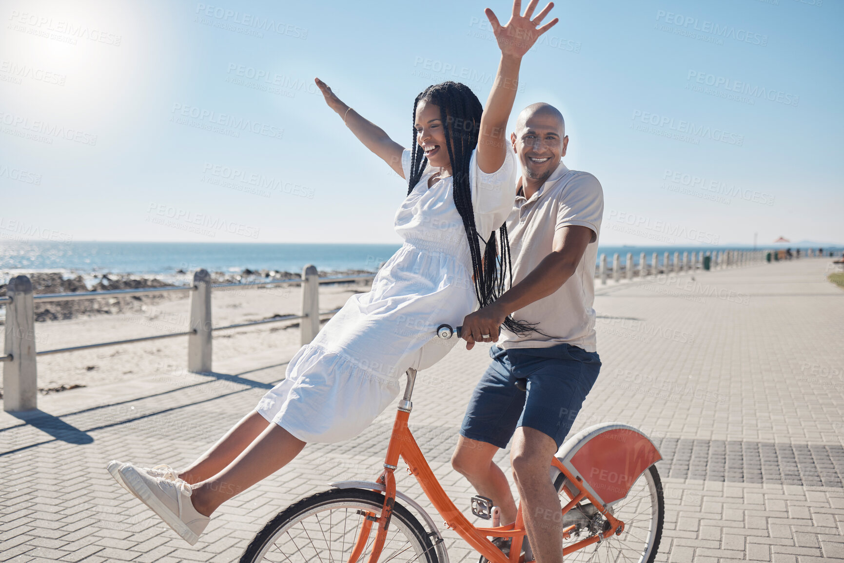 Buy stock photo Bicycle, beach and couple with freedom, travel and summer holiday in city sidewalk for wellness, love and care in sunshine. Mental health, black woman and cycling partner at ocean on blue sky mockup