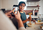 Funny child, phone and baking in home with mother taking photo for social media or food blog post in their home kitchen while making cake. Girl kid making comic face while cooking with a woman