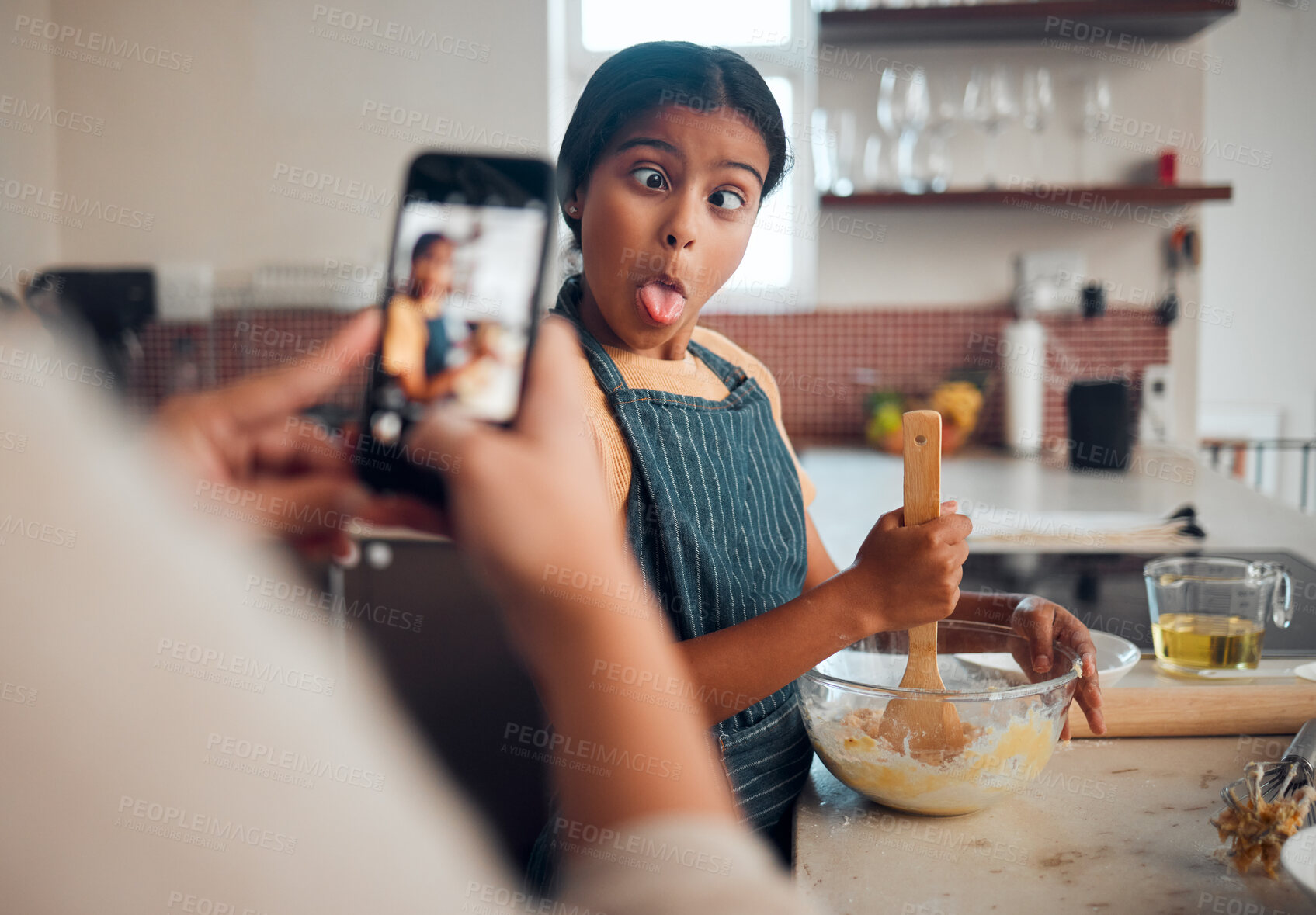 Buy stock photo Funny child, phone and baking in home with mother taking photo for social media or food blog post in their home kitchen while making cake. Girl kid making comic face while cooking with a woman