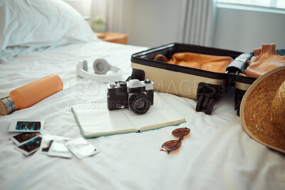 Buy stock photo Hotel, travel and bedroom with a suitcase, camera and pictures on bed on holiday, vacation or trip. Hospitality, motel luggage and room with hat, sunglasses and notebook, headphones and water bottle.