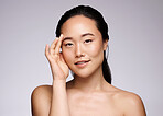 Woman, studio and skincare in portrait for beauty, wellness and cosmetic glow facial by grey backdrop. Asian model, cosmetics girl and cleaning for exfoliate, shine and makeup on face by background