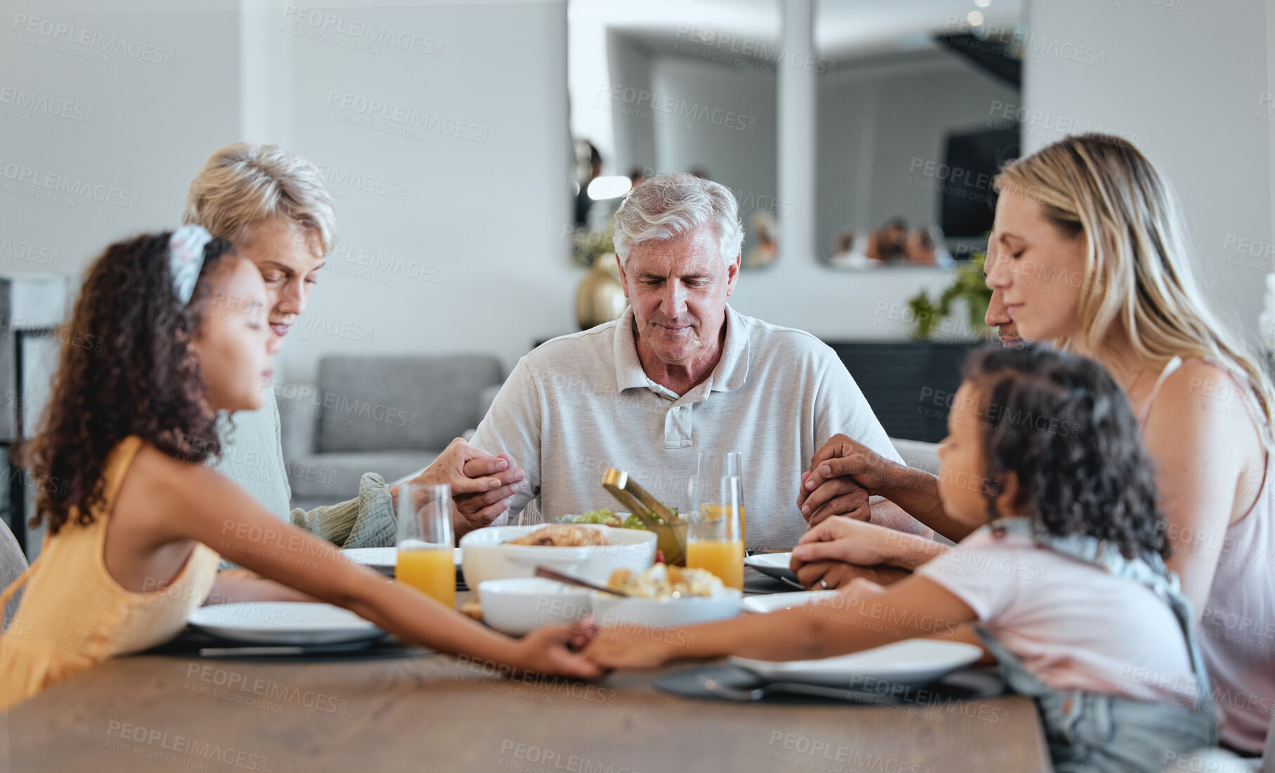 Buy stock photo Family, food and holding hands for prayer together at dining room table, worship support and relax quality time. Dinner, big family and Christian religion, praying and grace for supper buffet in home