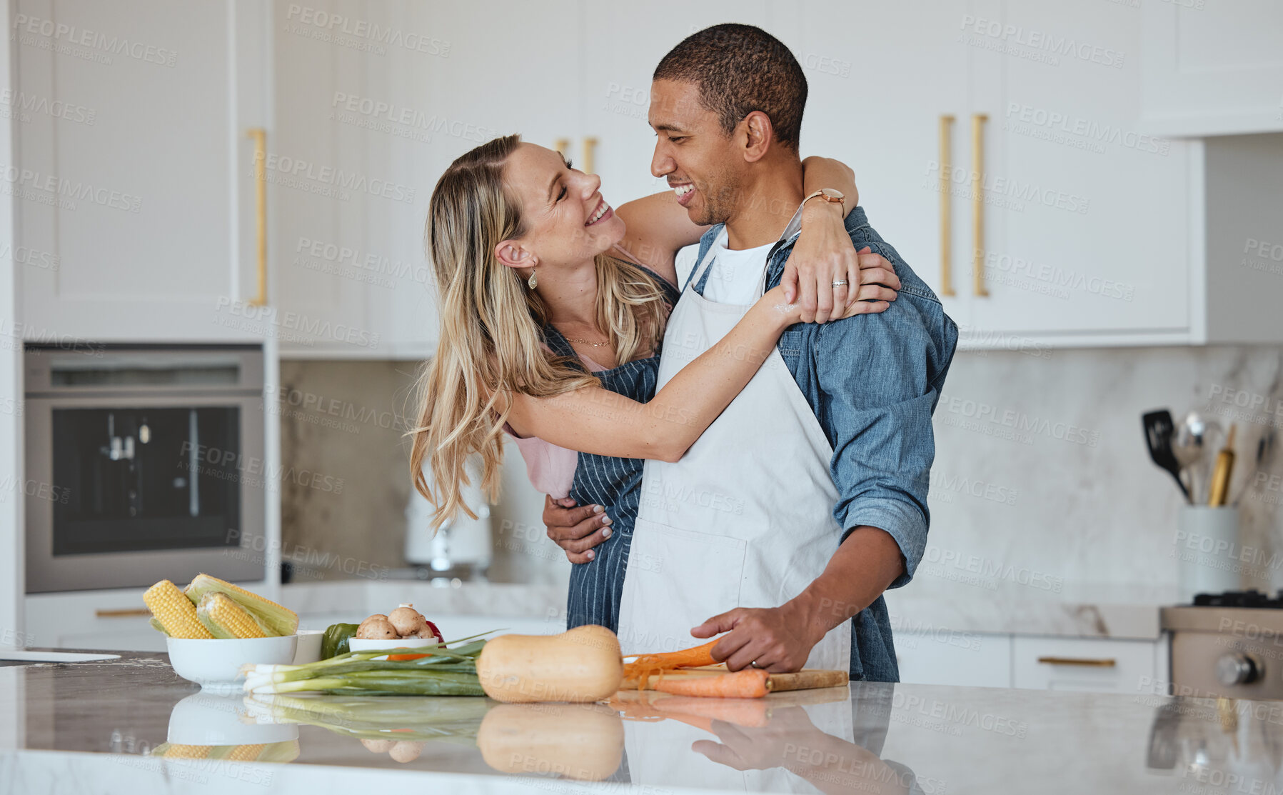 Buy stock photo Cooking, love or couple hug in a kitchen with healthy food diet in an interracial relationship or marriage at home. Carrot, vegetables or happy woman hugging romantic partner preparing a dinner meal