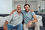 Portrait of a senior man with his adult son relaxing on a sofa together in the living room. Happy, smile and elderly male pensioner in retirement sitting and bonding with a young guy in family home.