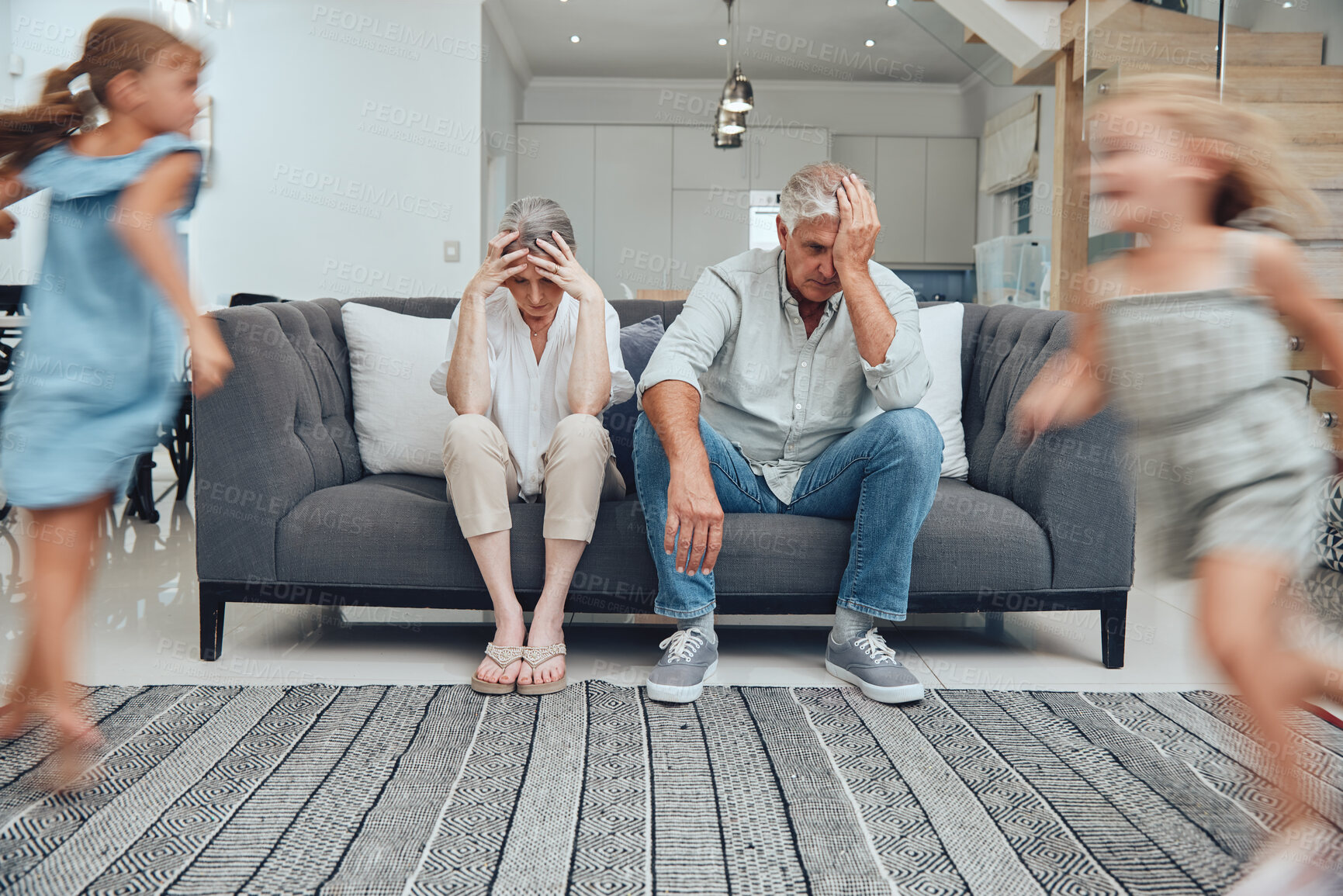 Buy stock photo Burnout headache, children running and parents on living room sofa with migraine from hyper active kids. Mental health problem, family stress and senior grandparents tired from babysitting adhd girl