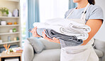 Hands, clean towels and woman with laundry, linen or cotton textile in stack at home. Spring cleaning, hygiene and female cleaner with fresh, cleaned or washed pile of fabric, towel or cloth in house