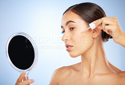 Buy stock photo Skincare, hand mirror and woman with serum, natural beauty and cosmetics on blue studio background. Makeup, female and oil for dermatology, luxury and smooth skin for wellness, healthcare and routine