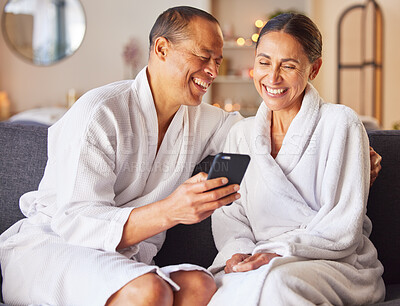 Buy stock photo Senior couple, spa and relax happy with phone on sofa, wellness center and luxury body care or streaming video online. Happiness, woman and man smile together, smartphone and beauty therapy gown