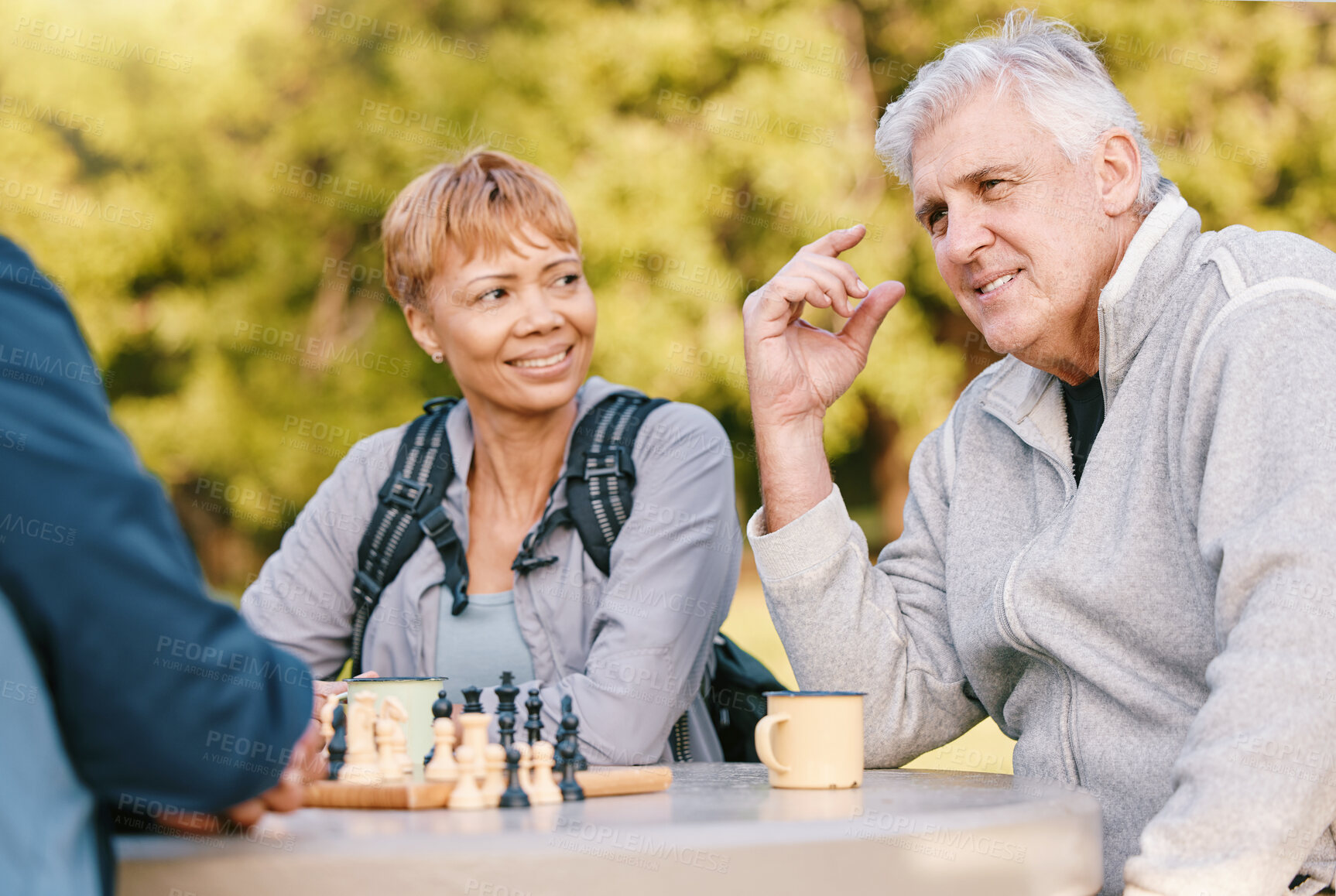 Buy stock photo Senior couple playing chess in nature after a wellness, fresh air and health walk in a garden. Happy, smile and elderly people talking, bonding and enjoying a board game together in a green park.