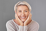 Portrait of one happy caucasian mature woman isolated against a grey copyspace background. Confident smiling senior woman looking cheerful while showing her natural looking teeth in a studio