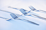 Fork, cutlery and symmetry with eating utensils on a table in an empty studio on a blue background from above. Kitchen, utensil and forks closeup ready for breakfast, lunch or dinner in a restaurant