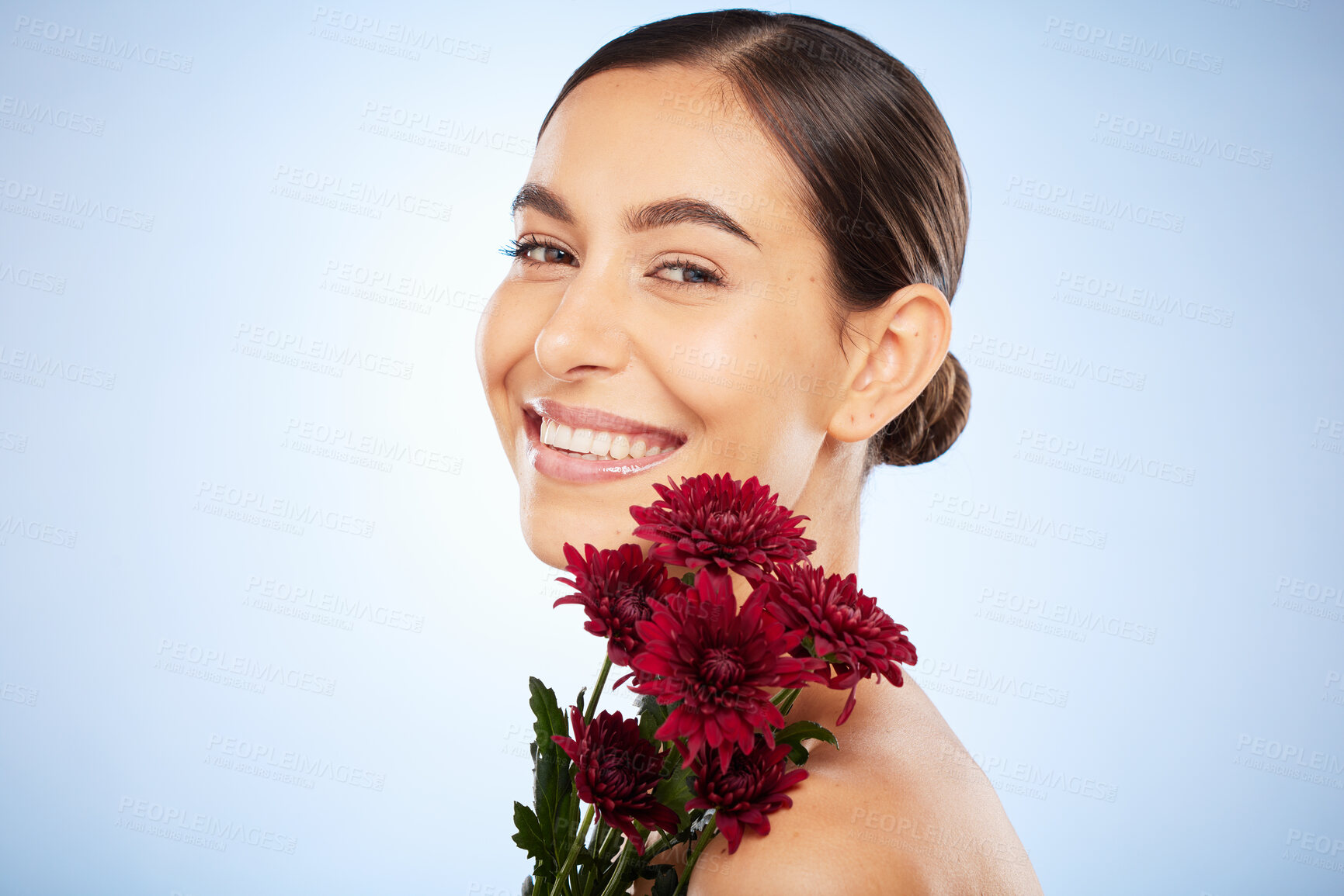 Buy stock photo Skincare, flowers and beauty portrait of woman on studio blue background for healthy skincare, wellness and luxury makeup in Spain. Face, smile and model with floral chrysanthemum for natural perfume